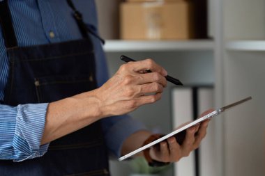 Bir tablet üzerine önemli bilgiler yazan Asyalı bir girişimci, modern bir e-iş ortamında çoklu görev becerileri sergiliyor.