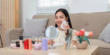 Rahat bir ortamda, genç bir kadın makyajını yaparken mutlu görünür, kendine özen gösterir ve güzellik rutiniyle güçlenir..