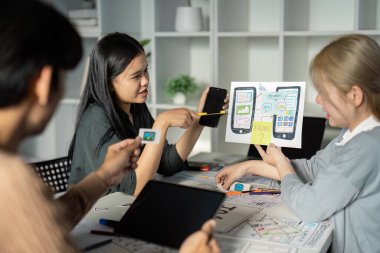 Modern ofis ortamında dijital aygıtlar ve kablolar kullanarak UX UI tasarımı üzerinde işbirliği yapan çeşitli takım.