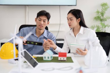 Mühendisler canlı bir ofis ortamında, minyatür modellerle çalışırken sürdürülebilir konut çözümleri planlamaya ve yenilenebilir enerji teknolojisini tartışmaya odaklandılar..