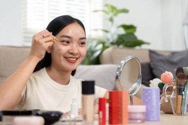 Işıl ışıl bir mekanda, bir kadın cildine yağ sürerken gülümser, cilt bakımı yoluyla verdiği hazzın ve güçlenmenin altını çizer..