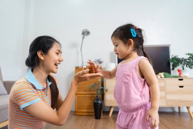 Neşeli bir anne yeni yürümeye başlayan çocuğuyla etkileşime giriyor, parlak ve davetkar bir oturma odasında oyuncağını paylaşıyor, iletişimi teşvik ediyor ve öğreniyor..