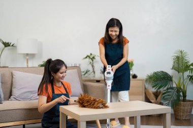 Temizlikçi modern bir evi etkin bir şekilde temizler, ev işlerini gösterir, süpürme ve toz alma gibi temel şeyleri gösterir..