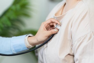 Şefkatli bir sağlık hizmeti sağlayıcısı, rutin sağlık izleme ve hasta bakımının önemini vurgulamak amacıyla bir hasta üzerinde steteskop muayenesi yapıyor..