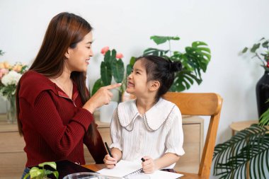Bir anne ve kız birlikte neşeli bir öğrenme anını paylaşıyor, ilişkileri geliştirmenin ve okul için güven inşa etmenin önemini vurguluyor..