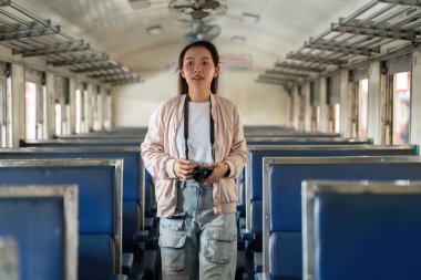 Tek başına bir yolcu boş bir tren vagonunda duruyor, kameralar ellerinde, yolculuklarını belgelemeye ve önlerindeki deneyimlere değer vermeye hazırlar..