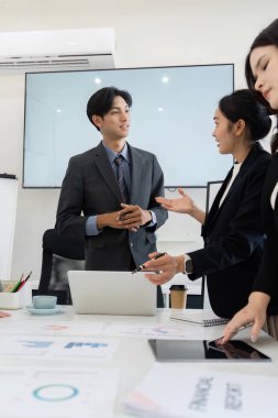 Bir iş ortamında, bir adam ve meslektaşları, stratejilerinde işbirliği ve yenilikleri vurgulayarak, verimli bir sohbete girişir..