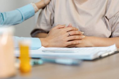 Sıcak bir danışma ortamında, bir sağlık hizmeti sağlayıcısı hastaya teselli edici destek sunarak, empati ve sağlık hizmetlerindeki önemi vurgular.