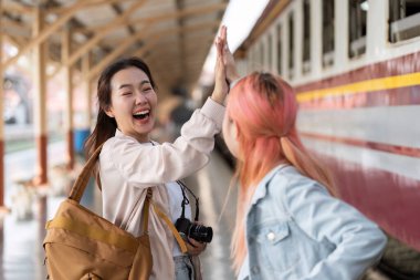 Tren istasyonunda birbirini heyecanla selamlayan iki arkadaş ortak bir maceraya atılmaya hazırlar. Neşeli ifadeleri dostluğun ve seyahatin özünü ifade eder..