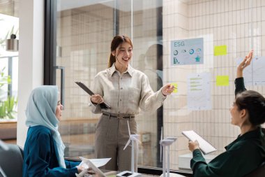 İşbirlikçi bir çalışma alanında, profesyoneller Çevre, Sosyal ve Yönetim ESG stratejileri hakkında bir tartışmaya girişirler. Odaklanmaları sürdürülebilirliğe ve sorumluluk sahibi işe bağlılığı yansıtıyor