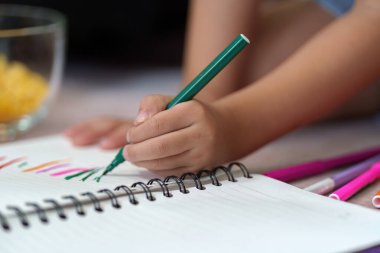 Genç bir sanatçı sanat yaratmak için renkli işaretler kullanarak yaratıcı bir ifade kullanır. Odak, eğitimin yaratıcılık yoluyla besleyici yönünü gösteriyor.
