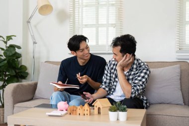 Bir LGBT çifti bütçeleri incelerken mali stratejilerini tartışıyor ve ortak hedeflerine ulaşmada birbirlerine destek olma kararlılıklarını vurguluyor.