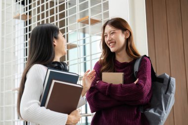 İki öğrenci, yeni öğrenim yılına ilişkin heyecanlarını paylaşarak, parlak bir akademik yolculuğa hazırlanırken gülüyor ve derslerini tartışıyorlar..