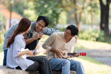 Arkadaşlığın özü, bir parkta toplanıp, ukulelelerle neşe içinde eğlenirken, kahkaha ve dostluk gösterisi yaparken yakalanır..