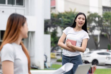 İki arkadaş okul ödevleri hakkında hararetli bir konuşma yaparken açık havada eğleniyorlar, işbirliği ve arkadaşlığı vurguluyorlar..