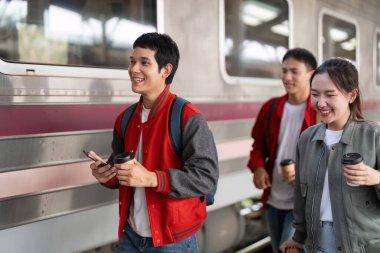 Üç genç yetişkin bir tren istasyonunda birlikte yürür, kahve içer, sohbet eder ve gülerek bir sonraki maceralarına atılırlar..