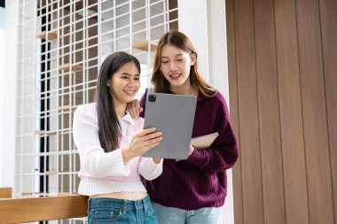 İki arkadaş, rahat ve çağdaş bir ortamda öğrenim oturumlarının keyfini çıkarırken, bir tablet üzerindeki notları ve kaynakları gözden geçirirler..