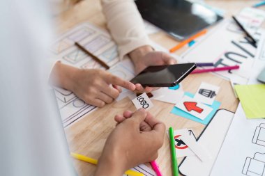 İki tasarımcı interaktif bir oturumda akıllı bir telefondan uygulama tasarımını tartışıyorlar. Logoları analiz eder ve yaratıcı süreçleri hakkındaki fikirleri paylaşırlar..