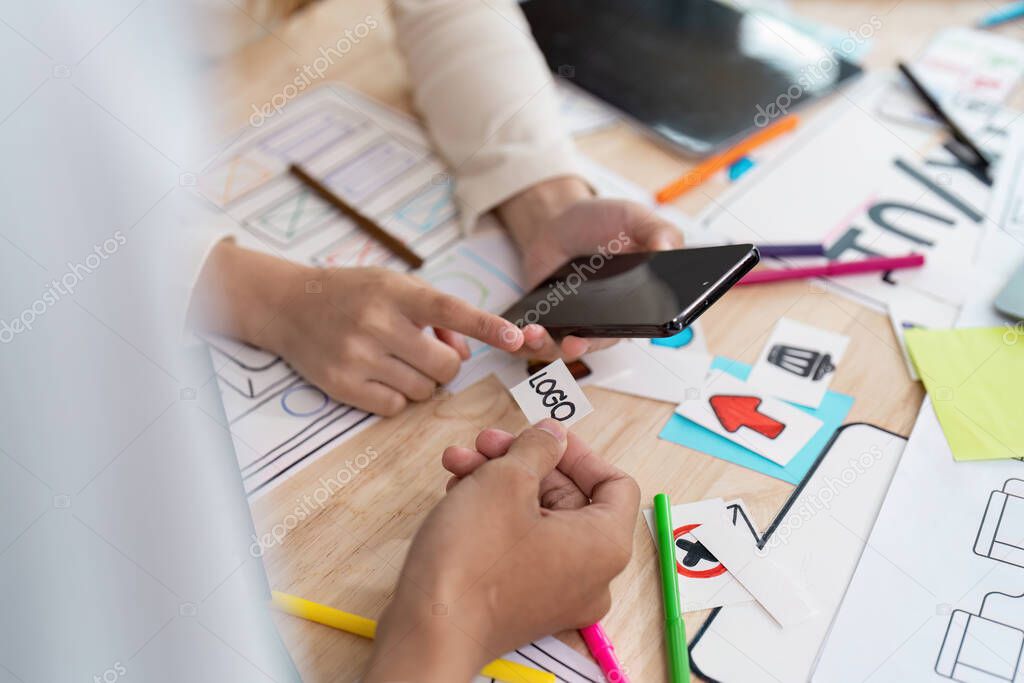 Two designers engage in an interactive session, discussing app design on a smartphone. They analyze logos and share ideas on their creative process.