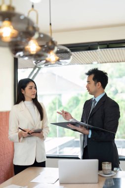 Profesyonel bir tartışma, bir erkek ve bir kadın proje planları üzerinde çalışırken devam eden çalışmalarına katkıda bulunan fikirler alışverişinde bulunur..