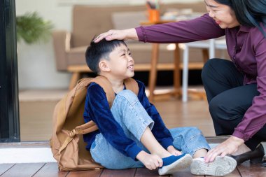 Şefkatli bir anne oğluna ayakkabıları ile yardım eder, okula hazırlanırken ona destek olur ve onları besleyen bağı gösterir..