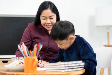 Eğitimde desteğin önemini vurgulayan kendini işine adamış bir çocuk, aile üyesinden cesaret alırken ödevlerine çalışır..