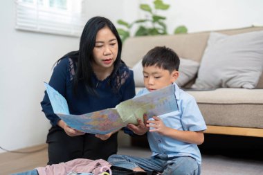 Bir anne ve oğlu birlikte oturur, aile tatillerini planlamak için haritaya bakar, keşfin ve seyahatin heyecanını vurgularlar..