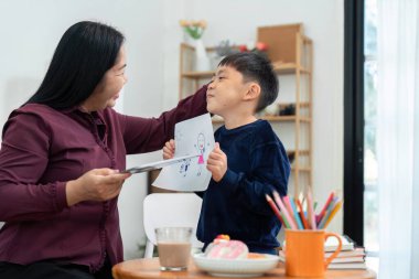 Yaratıcılığını sevgiyle öven annesine çizimini gururla gösteren genç bir çocuk, çocuk sanatsal gelişiminde desteğin önemini vurguluyor..