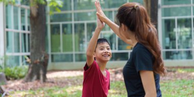 Genç bir erkek ve bir kadın birlikte bir egzersizi tamamladıktan sonra coşkuyla beşlik çakıyor, neşe ve güçlü bir aile bağını yansıtıyor..