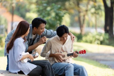 Bir grup arkadaş, biri tutkuyla şarkı söylerken, diğeri ise ukulelelerde yaratıcılığı ve yoldaşlığı yansıtan neşeli bir müzik anını paylaşıyor..