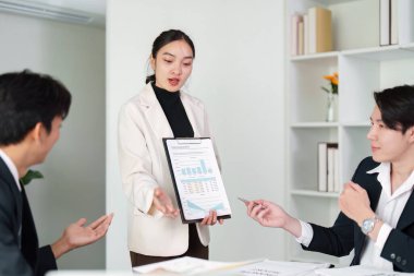 İş toplantısında finansal verileri sunan bir ekip, profesyonel bir ortamda takım çalışması ve etkili iletişimi vurguladı.