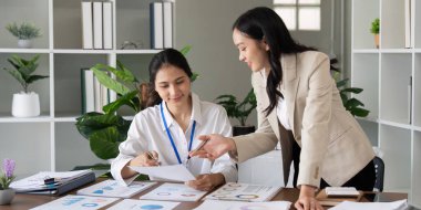 İki iş adamı parlak bir ofiste rapor ve stratejileri tartışıyor, takım çalışması ve yenilik sergiliyorlar.