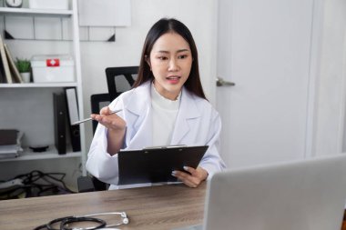 Bir genel pratisyen hekimin bir hastaya takip muayenesi yapması, sağlık sonuçlarına ve devam eden tedavi planlarına odaklanması.