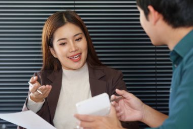 Güncellemeleri paylaşan ve modern ofis ortamında iş planlarını tartışan iki meslektaş, işbirlikçi bir çalışma ortamını destekliyor.