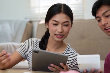 Bir tablet ve mali belge kullanan genç çift, paralarını etkili bir şekilde yönetmek için çağdaş yöntemler benimseyerek finansal hedefleri üzerinde işbirliği yapıyor..