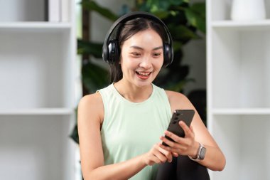 Genç bir kadın kulaklıkla müzik dinliyor, rahatlama ve farkındalık anında gülümsüyor..