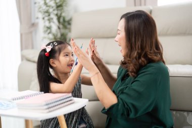 Bir anne ve kızı evde eğlenceli bir anı paylaşıyor, eğlenceli bir el oyunu oynuyorlar. Bu neşeli etkileşim, okula dönüş sezonuyla ilgili heyecan ve bağları vurguluyor..