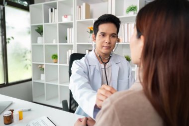 Hastanın muayenesi sırasında steteskop kullanan bir pratisyen hekim, sağlık hizmetlerindeki teşhis sürecini betimliyor..