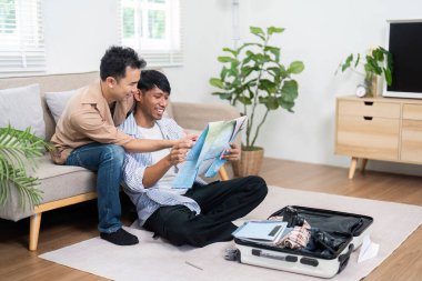 Çift, seyahat detaylarını telefonlarında kontrol ederken ve seyahat programlarını incelerken hafif bir anı paylaşıyor, ilerideki yolculuklarının heyecanını gösteriyor.