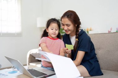 Şefkatli bir anne ve kızı eğlenceli bir öğrenme aktivitesine girişiyor, evde çocuk eğitimini geliştirmek için bir dizüstü bilgisayar kullanarak bir yandan da besleyici bir ilişki kuruyorlar..