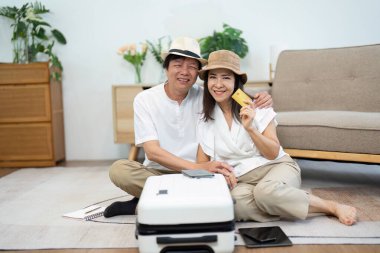 Yaşlı bir çift evde bavullarını hazırlarken gülümseyerek seyahat gerekliliklerini gösteriyor. Mutlulukları, altın yıllarındaki macera ve arkadaşlığın heyecanını yansıtır..