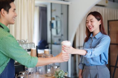 Müşteri, arkadaş canlısı bir baristadan taze kahve alır, sürdürülebilir bir kafede toplum ve kaliteli hizmeti somutlaştırır..