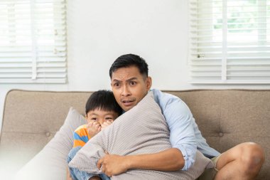 Bir baba oğlunu korku filmi sahnesinde rahatlatır. Aile filmi gecesinin keyfini çıkarırken güçlü bağlarını ve duygusal bağlarını gösterir..