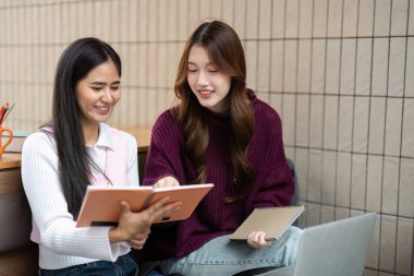 İki arkadaş ödevlerini birlikte gözden geçirir, notlarını ve fikirlerini rahat bir ortamda paylaşırlar. Takım çalışmaları kişisel gelişimi ve akademik başarıyı sembolize eder..