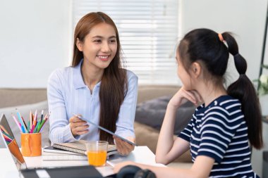 Gülümseyen bir eğitimci, evde olumlu ve ilgi çekici bir öğrenme atmosferi yaratan bir öğrenciyle görüşlerini paylaşır..