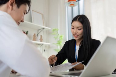 Finansal danışman, modern bir ofisteki müşteriye, mesleki danışmanlık sunan vergi belgelerini açıklar..