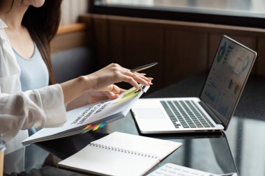 Görevlerine odaklanan genç bir kadın, bilgisayarında yazarken belgelerini ve çizelgelerini düzenliyor ve verimli çalışma alışkanlıkları sağlıyor..