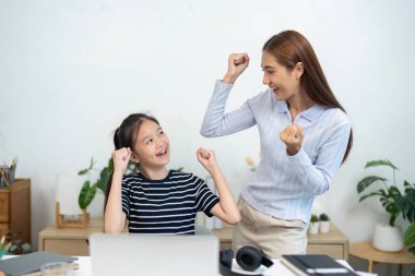 Bir kız ve annesi çevrimiçi öğrenmedeki başarılarını kutlarken ve okula dönüş heyecanını gösterirken neşeli bir an..