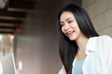 Genç bir kadın çevrimiçi bir toplantıda uzaktan çalışma ve dijital iletişimin yeni çağını sergilerken gülümsüyor..