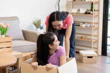 İki kadın yeni evlerine taşınırken neşe ve kahkahayı paylaşırken, biri karton bir kutuda saklanmış, diğeri de neşeyle izliyor..